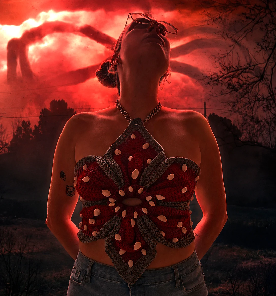 Maker wearing a red crochet Demogorgeous top beneath a dramatic red sky