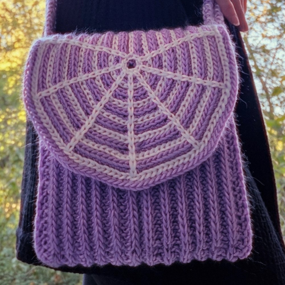 Purple crocheted crossbody bag with a white spiderweb detail